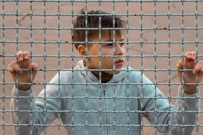 Portrait of boy playing by fence