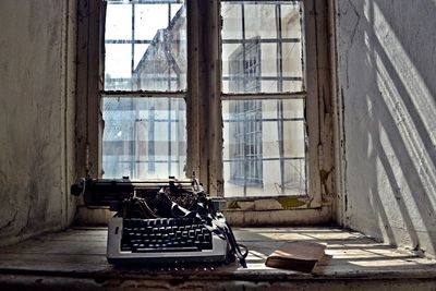 Old broken typewriter by book on window sill