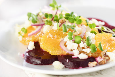 Orange salad with baked beetroot, goat cheese, microgreens and nuts.