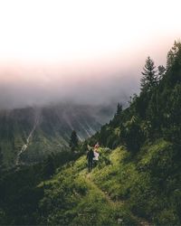 Rear view of people walking on mountain against sky