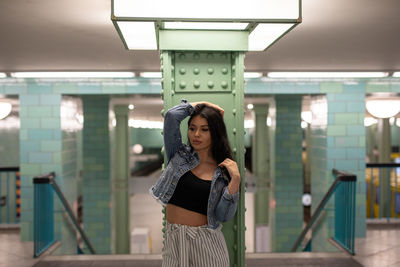 Young woman looking away while standing against column