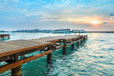 Pier over sea against sky during sunset