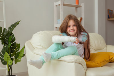 Portrait of smiling woman sitting on sofa at home