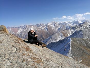 Woman sitting on rock against mountains