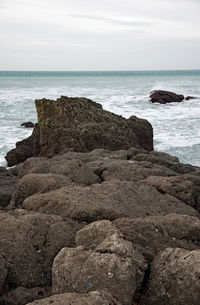 Rock formation on beach against sky