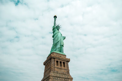 Low angle view of statue of liberty against cloudy sky