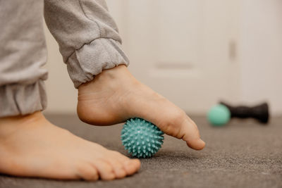 Woman doing flatfoot correction gymnastic exercise using massage ball. myofascial relaxation