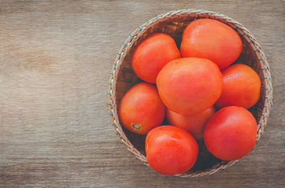 Directly above shot of fresh tomatoes in basket on wooden table