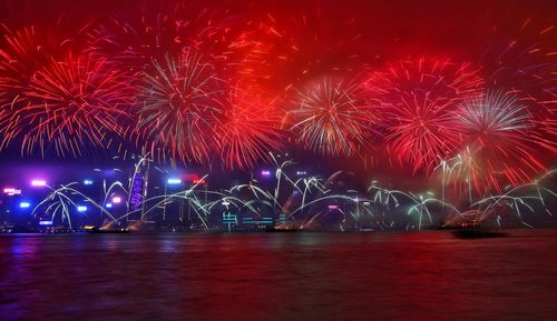 Firework display over sea against sky at night