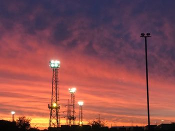 Low angle view of illuminated street lights against orange sky