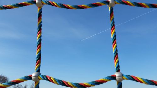 Low angle view of multi colored ropes against blue sky
