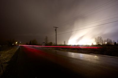 Light trails on road against sky at night