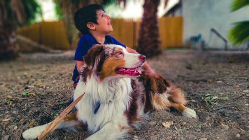 Portrait of a dog and a boy  looking away in the same direction.