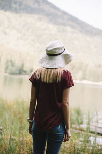 Rear view of woman standing by lake