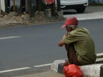 Rear view of man sitting sitting on road in city