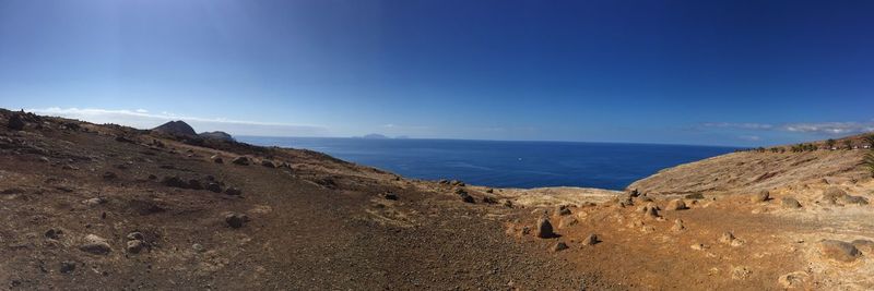 Scenic view of sea and mountains against blue sky