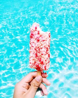Close-up of hand holding ice cream cone in swimming pool