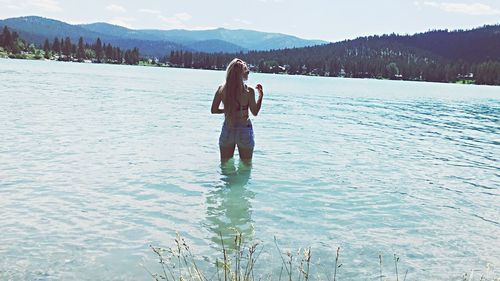 Full length of woman standing on lake against mountain