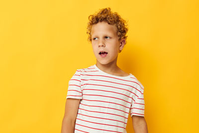 Portrait of boy standing against yellow background