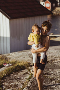 Smiling brother carrying baby sister while walking on archipelago