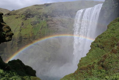 Scenic view of rainbow over waterfall