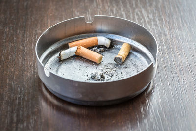 Close-up of cigarette butts in ashtray at table