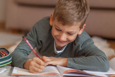 Boy writing on book in living room at home 