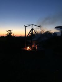 Silhouette of fire on field against sky during sunset