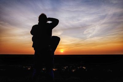 Silhouette man standing by sea against sky during sunset