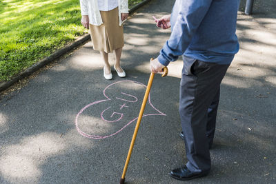 Senior couple drawing love heart with initials on tarmac