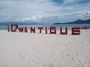 Text on beach against sky