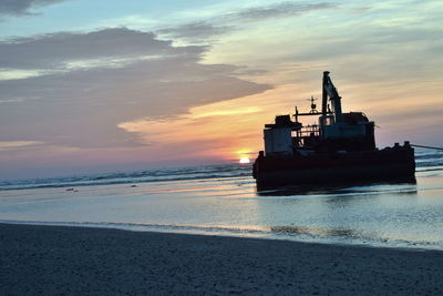 Boat on beach against sky during sunset