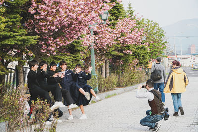 People on street amidst flowering trees in city