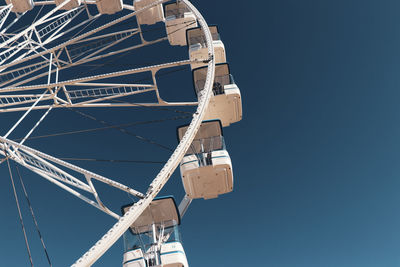 Low angle view of ferris wheel against clear blue sky