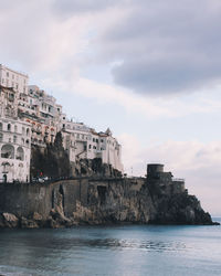 Buildings by sea against sky