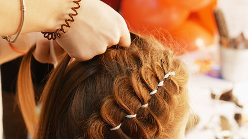 Cropped hands of female hairstylist styling girl hair