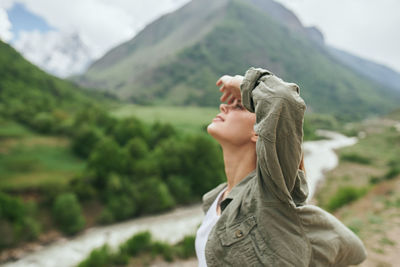 Side view of young woman against mountain range