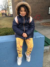 Portrait of girl sitting on retaining wall