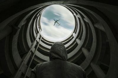 Low angle view of man standing in building against airplane