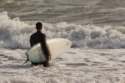 Rear view of man surfing in sea