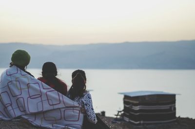 Rear view of mother and daughters sitting outdoors