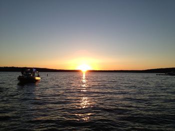 Boat sailing in sea against clear sky during sunset