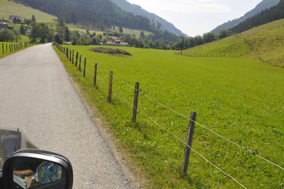 Scenic view of road amidst field against mountains