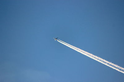 Low angle view of vapor trail against blue sky