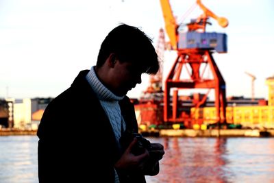 Man holding camera while standing against commercial dock