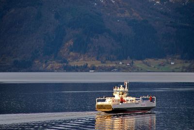 Boat sailing in sea against mountain