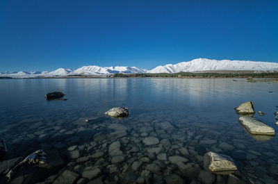 Scenic view of frozen lake against clear blue sky