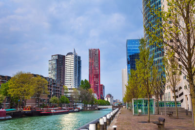 Buildings by river against sky in city