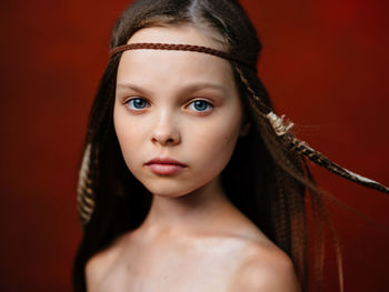 Close-up portrait of young woman against red background