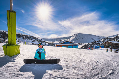 Portrait of a woman snowboarder sitting on snow and looking at camera, andorra